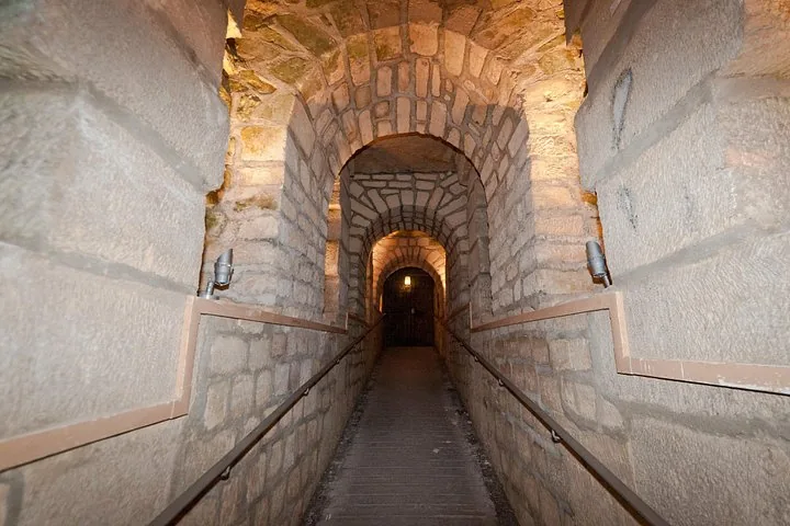 Une allée en pierre menant à travers les tunnels voûtés en pierre des Catacombes.