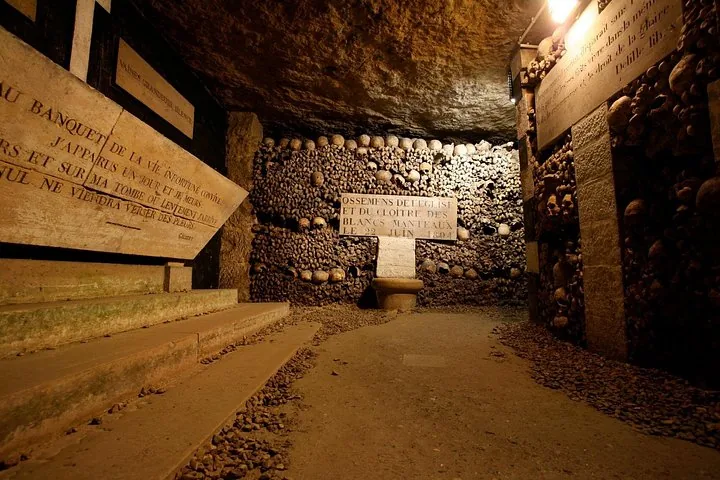 Una camera sotterranea con targhe di pietra e un muro fatto di ossa umane.